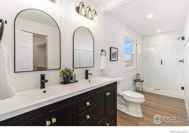 bathroom with a sink, a shower stall, toilet, and wood finished floors