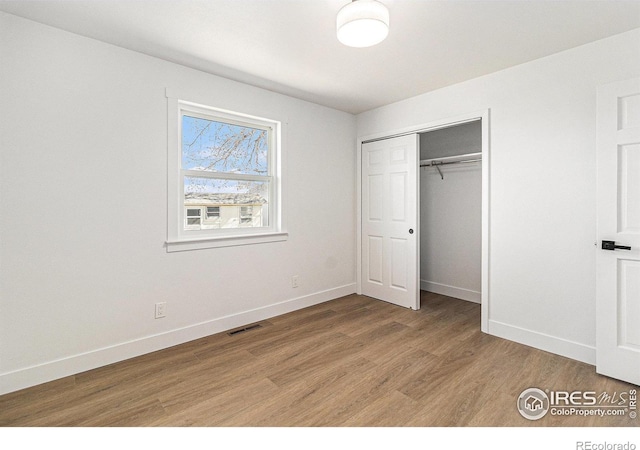 unfurnished bedroom featuring light wood-style floors, a closet, visible vents, and baseboards