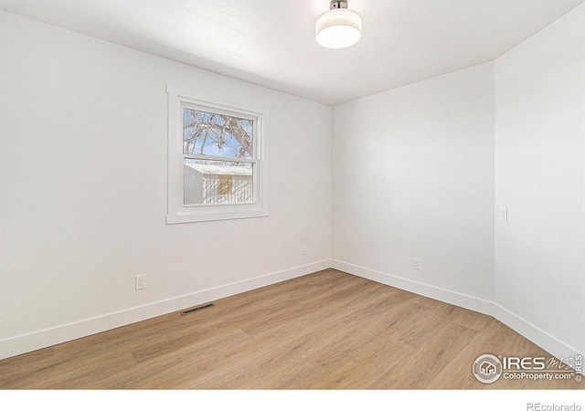 spare room with baseboards, visible vents, and light wood-style floors