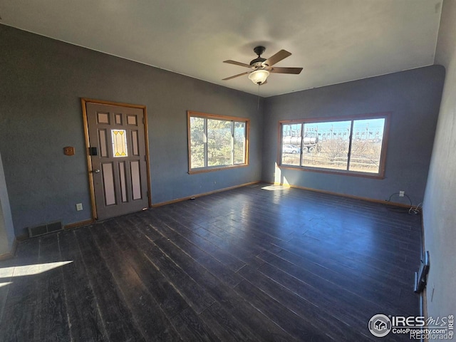 interior space featuring dark wood-style flooring, visible vents, ceiling fan, and baseboards