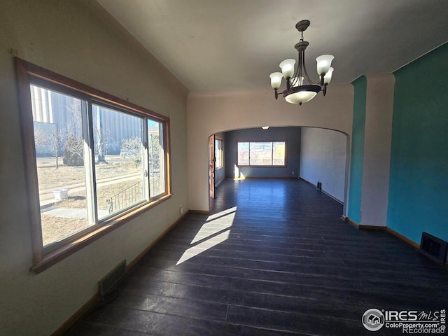 unfurnished room featuring arched walkways, a notable chandelier, visible vents, wood finished floors, and baseboards