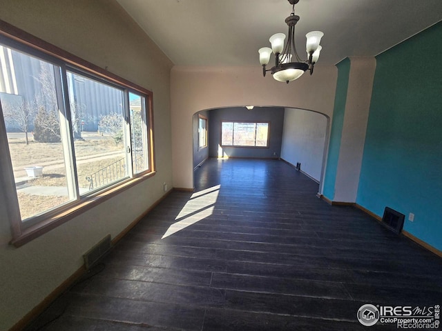 unfurnished dining area featuring baseboards, visible vents, arched walkways, and wood finished floors