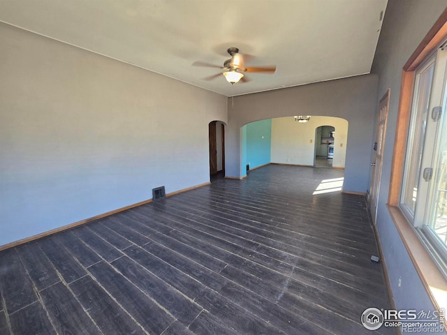 spare room featuring visible vents, arched walkways, a ceiling fan, baseboards, and wood finished floors