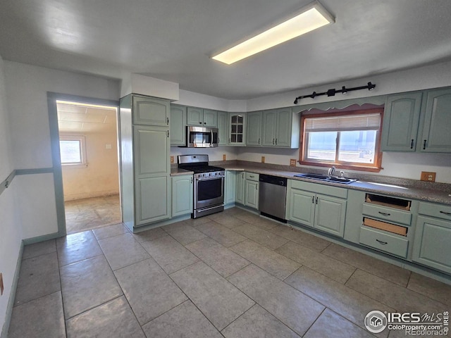 kitchen with green cabinets, stainless steel appliances, a sink, and a wealth of natural light