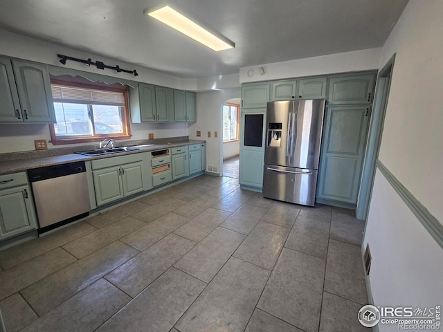 kitchen featuring plenty of natural light, arched walkways, appliances with stainless steel finishes, a sink, and green cabinetry