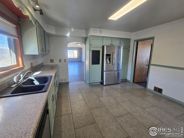 kitchen with visible vents, arched walkways, appliances with stainless steel finishes, light countertops, and a sink