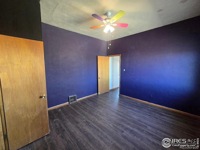 empty room featuring ceiling fan, visible vents, baseboards, and wood finished floors