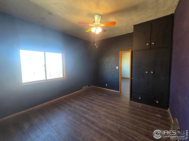 unfurnished bedroom with visible vents, a textured ceiling, baseboards, and dark wood-type flooring