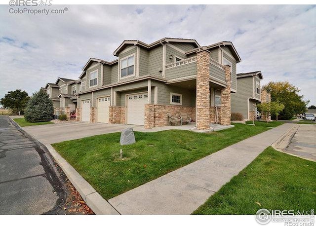 view of front facade featuring a balcony, a garage, driveway, stone siding, and a front yard