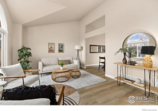 living room featuring high vaulted ceiling, wood finished floors, and baseboards