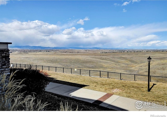 view of yard with a rural view, fence, and a mountain view