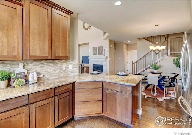 kitchen with a peninsula, a chandelier, dark wood finished floors, and freestanding refrigerator