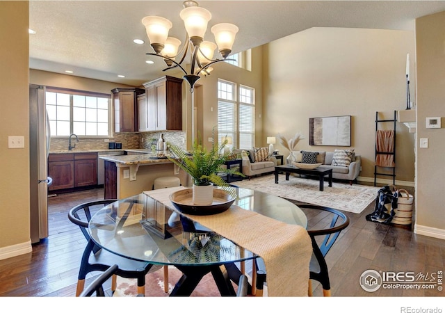 dining space with dark wood-style floors, a notable chandelier, and a healthy amount of sunlight