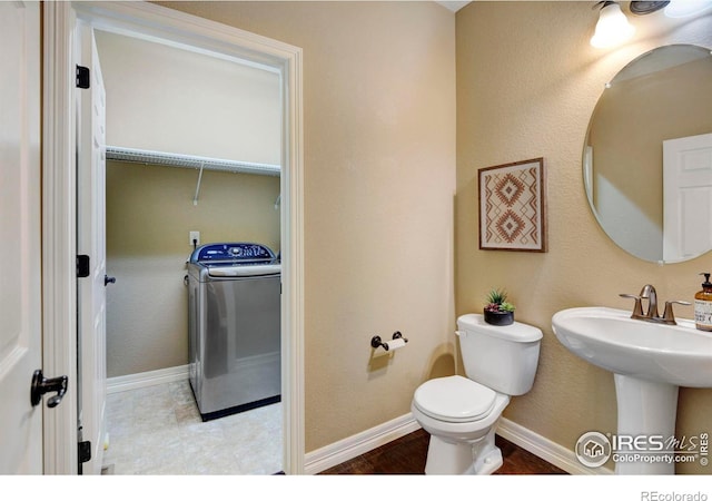 bathroom featuring washer / clothes dryer, a sink, toilet, and baseboards