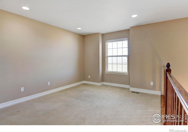 spare room with baseboards, recessed lighting, visible vents, and light colored carpet