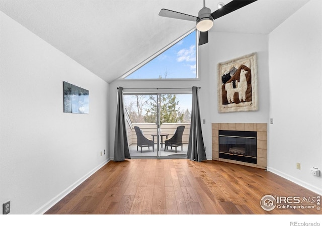 unfurnished living room featuring baseboards, ceiling fan, a tiled fireplace, and wood finished floors