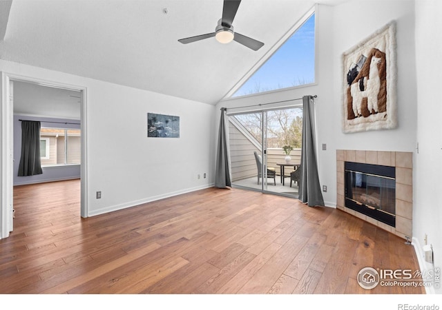 unfurnished living room featuring baseboards, ceiling fan, hardwood / wood-style floors, a fireplace, and high vaulted ceiling