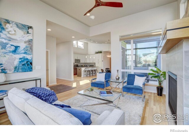 living room with recessed lighting, a healthy amount of sunlight, a fireplace, and light wood-style flooring