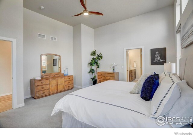 bedroom featuring baseboards, visible vents, light carpet, and a high ceiling