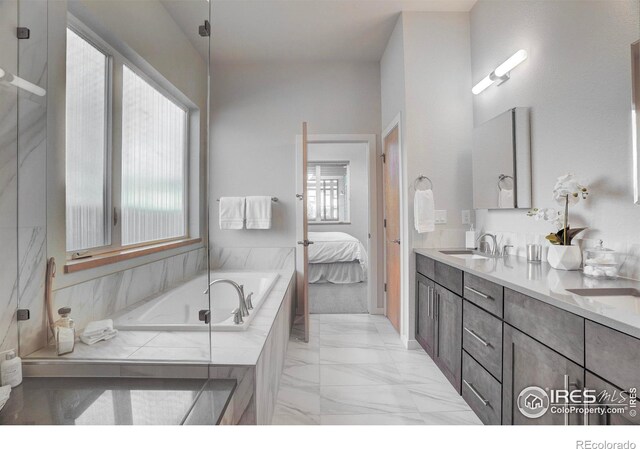 bathroom featuring marble finish floor, double vanity, a sink, ensuite bath, and a bath