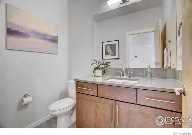 half bathroom featuring vanity, toilet, and baseboards