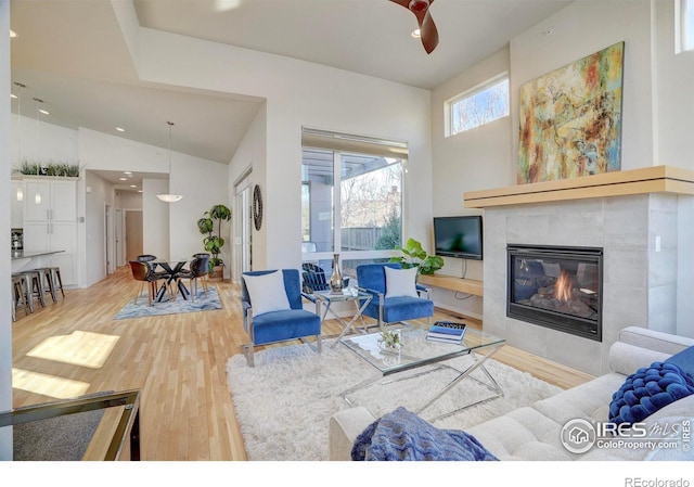 living room featuring recessed lighting, high vaulted ceiling, wood finished floors, and a tile fireplace