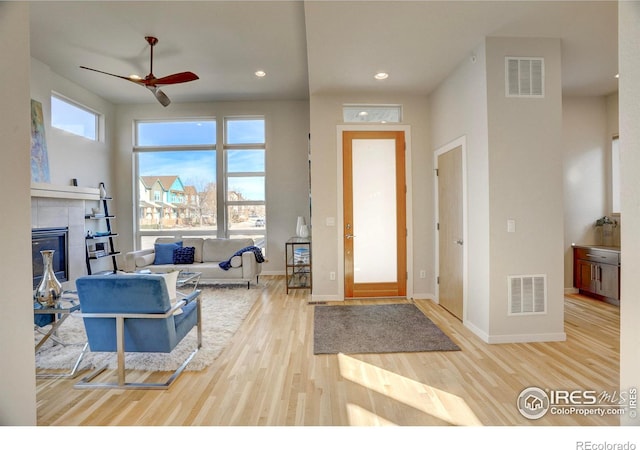 foyer entrance with a wealth of natural light, light wood-type flooring, a fireplace, and visible vents