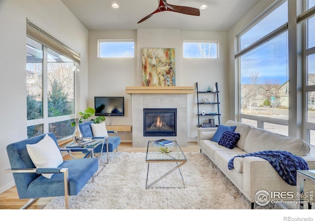 living room with a tile fireplace, wood finished floors, a wealth of natural light, and recessed lighting