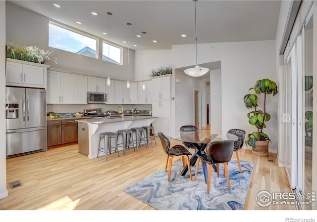 dining room with visible vents, recessed lighting, a towering ceiling, and light wood-style floors