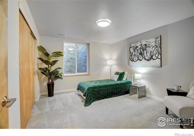 bedroom with a textured ceiling, visible vents, baseboards, a closet, and carpet