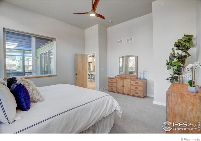 carpeted bedroom featuring baseboards, a high ceiling, visible vents, and ceiling fan