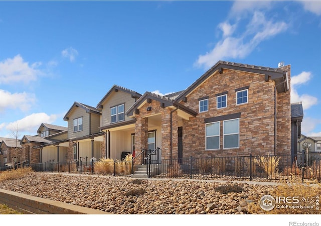 view of front of home with stone siding and a fenced front yard