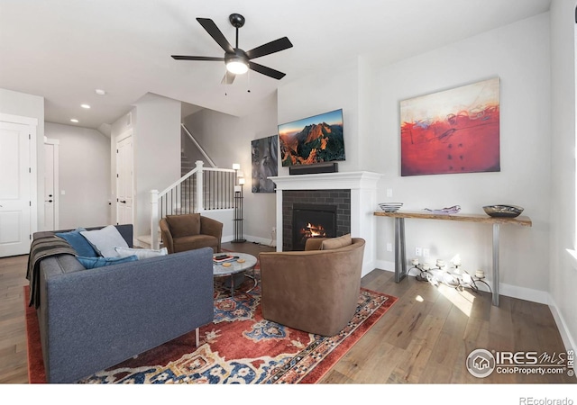 2748 Prairie Flax St, Berthoud, CO 80513 - living room with a ceiling fan, stairway, wood finished floors, a brick fireplace, and baseboards
