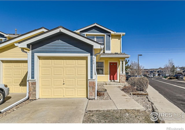 view of front of house with stone siding, a garage, and driveway