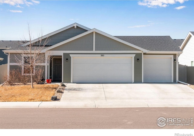 single story home with an attached garage, a shingled roof, and concrete driveway