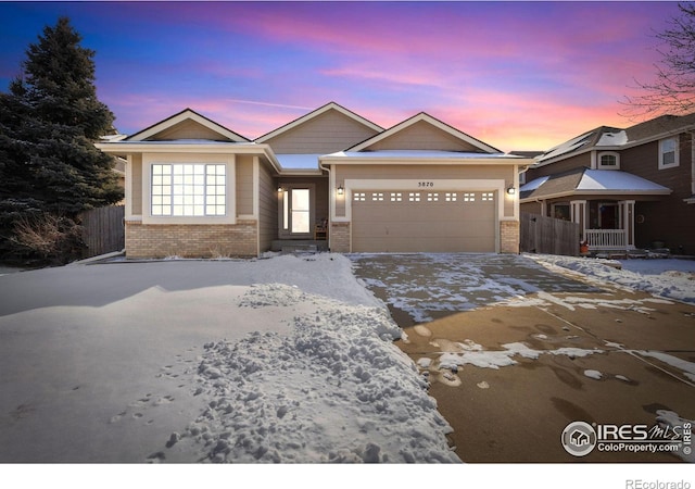 view of front of house with a garage, brick siding, fence, and driveway