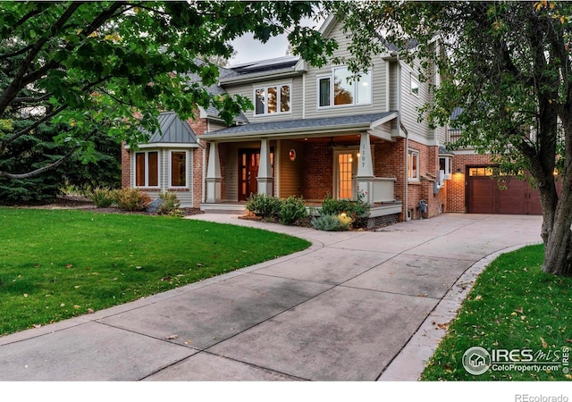 view of front of property with a porch, brick siding, driveway, roof mounted solar panels, and a front lawn