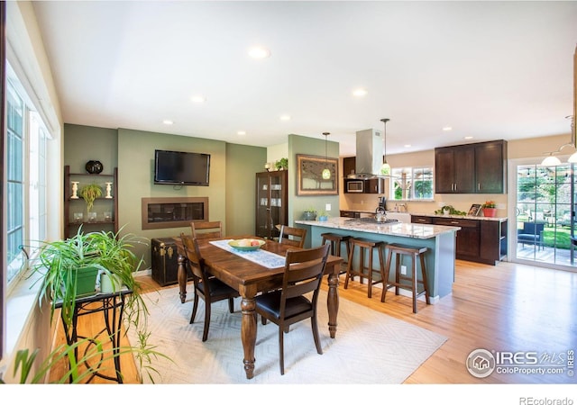 dining room with light wood-style floors, recessed lighting, and a glass covered fireplace