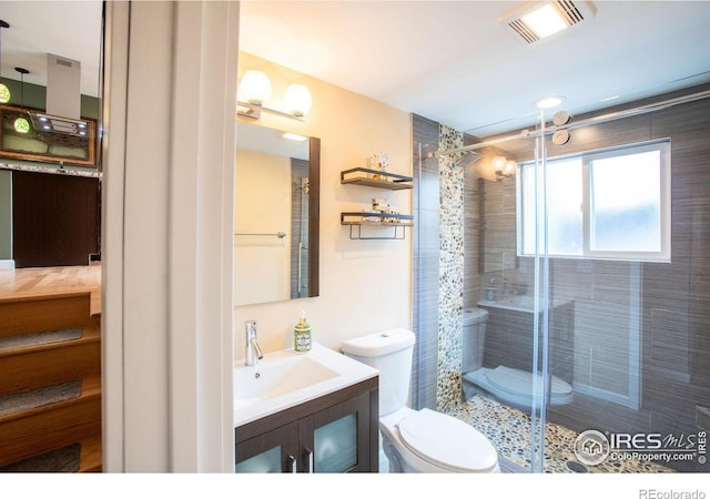 bathroom featuring visible vents, a shower stall, toilet, and vanity