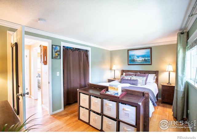 bedroom featuring ornamental molding, light wood-style flooring, and baseboards