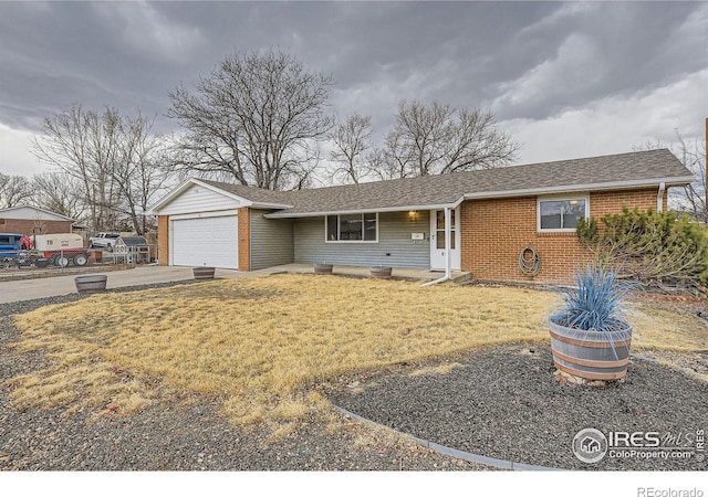 ranch-style home with a garage, brick siding, a shingled roof, concrete driveway, and a front lawn