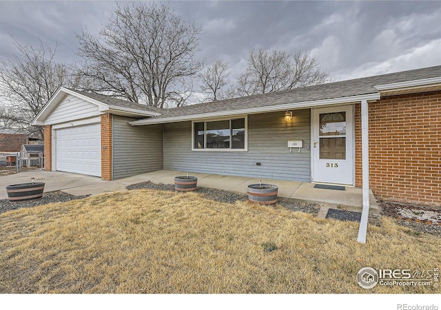 single story home featuring a garage, roof with shingles, a front yard, and brick siding