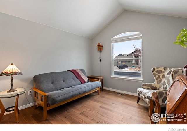 living area with lofted ceiling, wood finished floors, visible vents, and baseboards