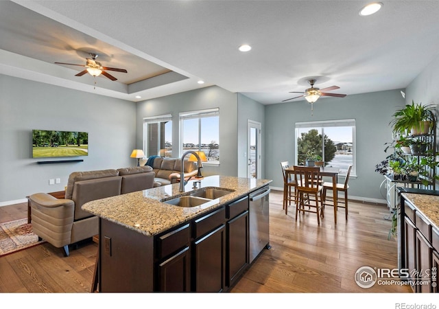 kitchen with open floor plan, a sink, stainless steel dishwasher, and wood finished floors