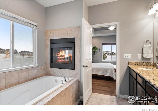 ensuite bathroom featuring a tiled fireplace, connected bathroom, vanity, a bath, and tile patterned floors