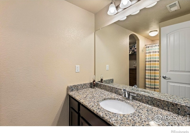 bathroom with visible vents, a textured wall, vanity, and a shower with shower curtain