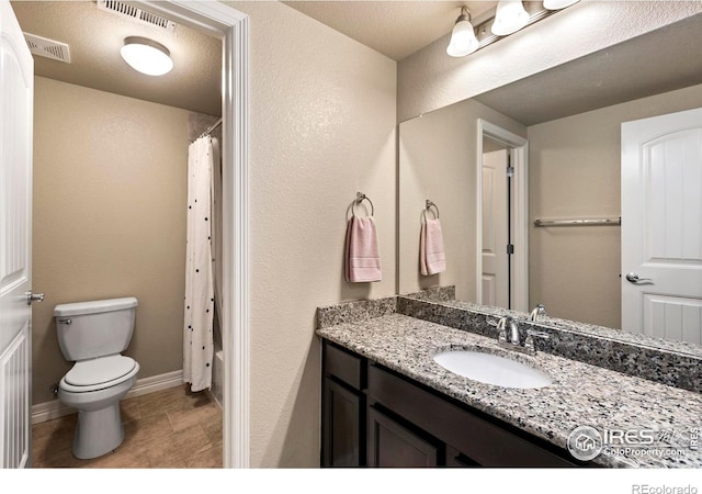 full bath featuring toilet, vanity, visible vents, and baseboards