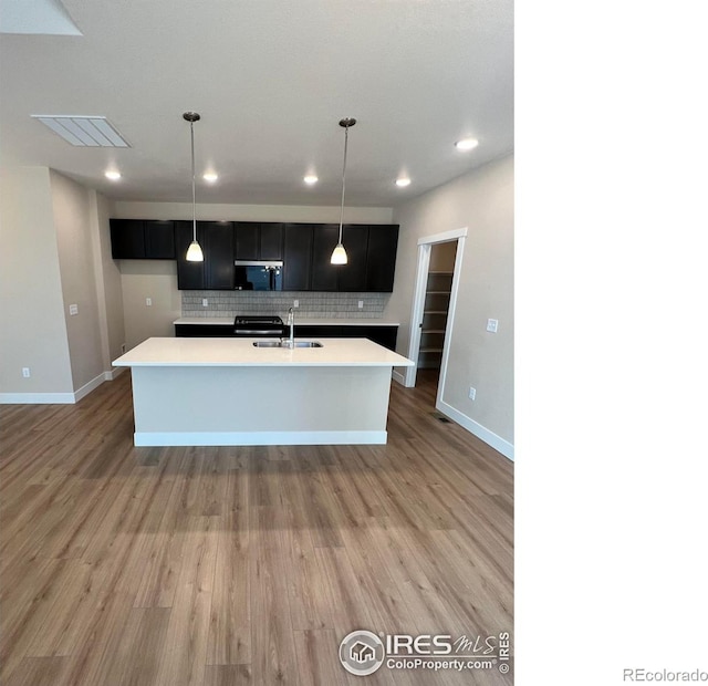 kitchen with tasteful backsplash, light countertops, stainless steel microwave, visible vents, and a sink