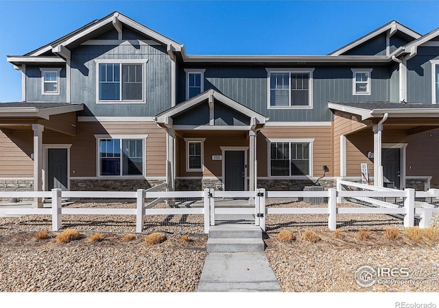 view of front of house featuring stone siding, a fenced front yard, and a gate