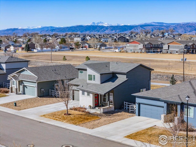 view of front of house featuring an attached garage, a mountain view, a shingled roof, driveway, and a residential view